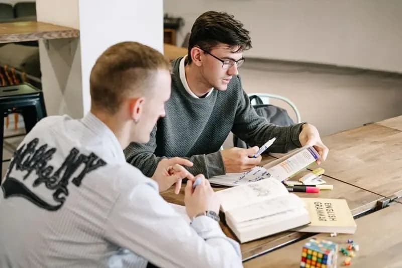 Two students studying English grammar books together
