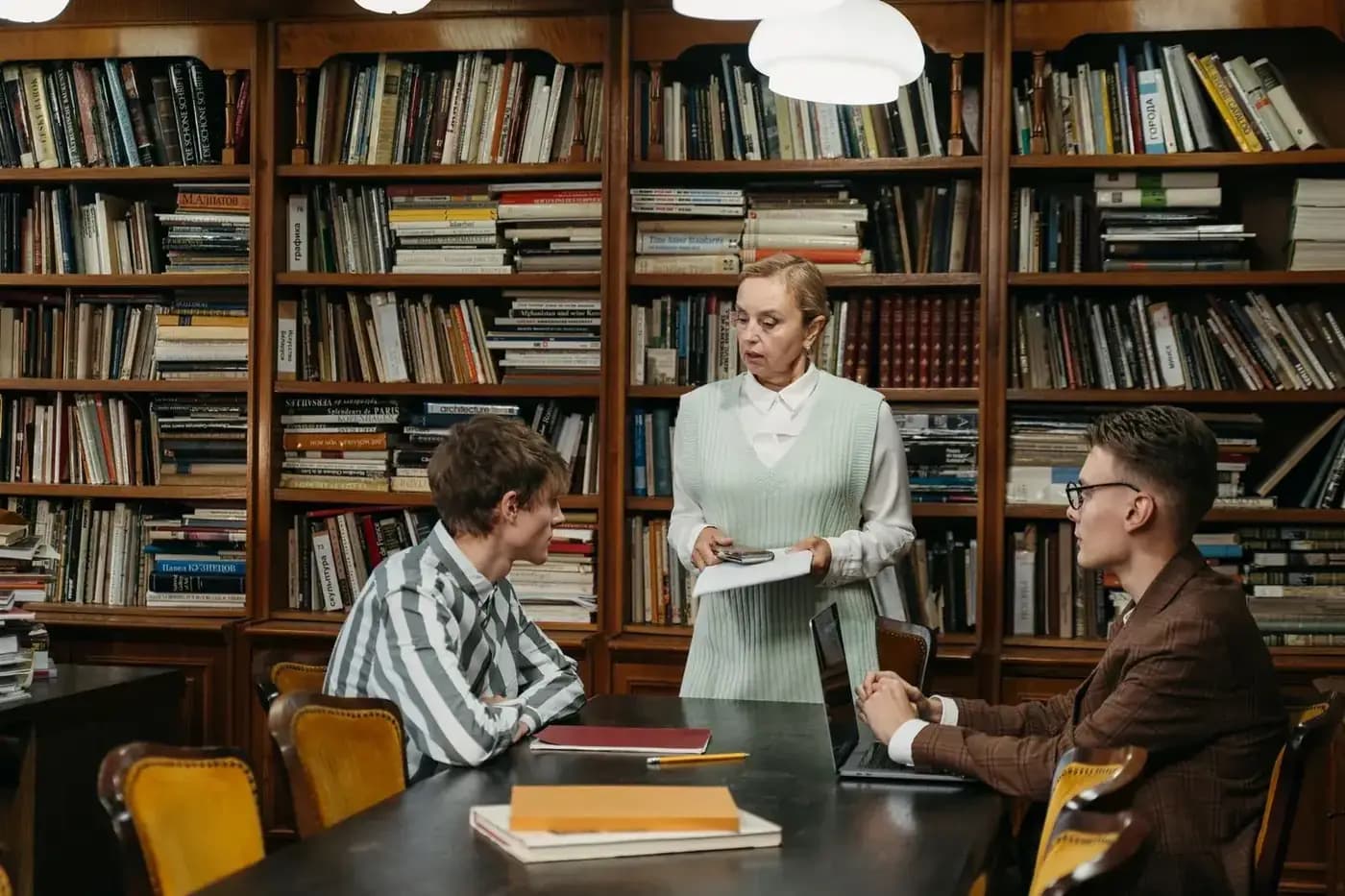 University staff member speaking with two students in a library